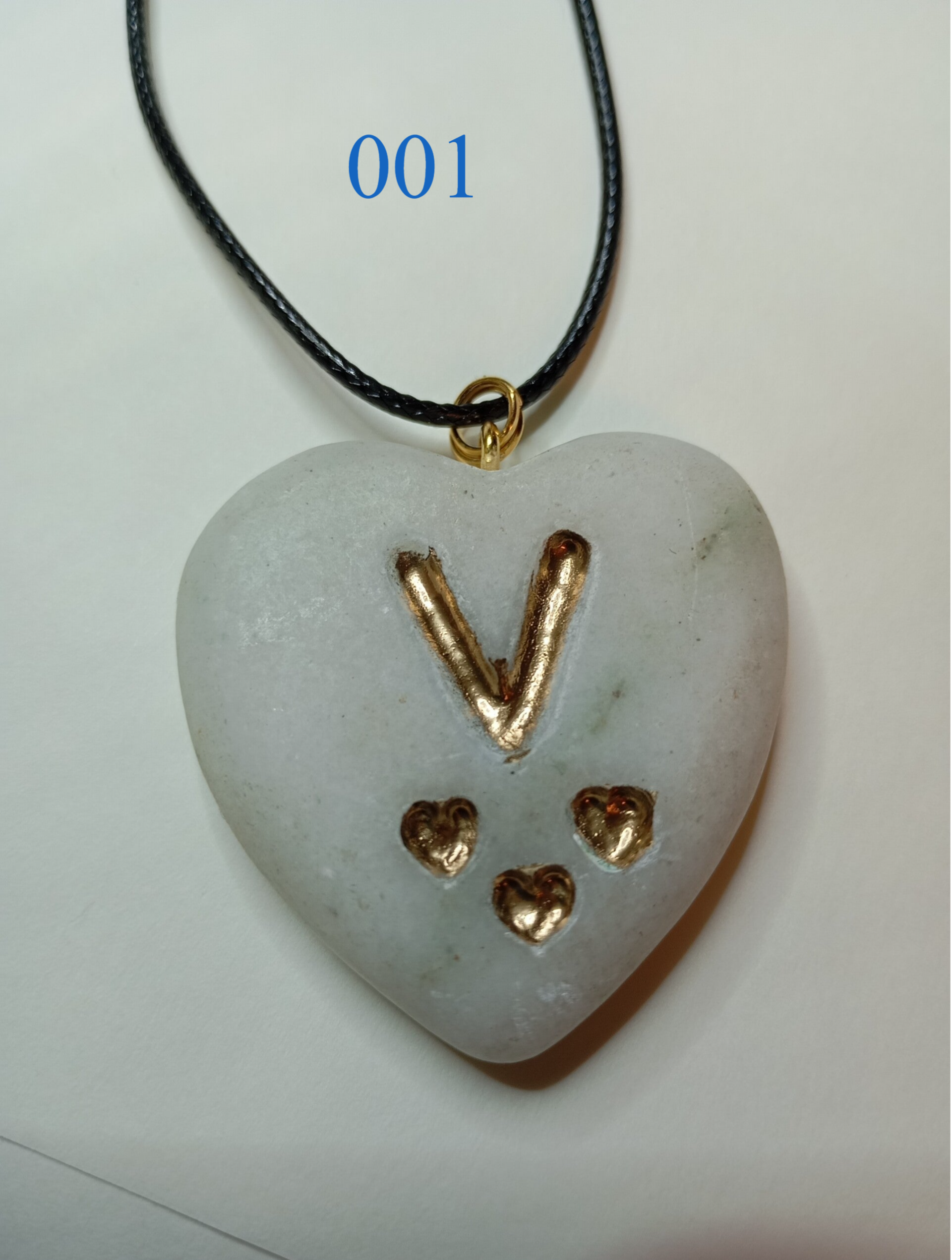 Halskette aus Naturstein mit eingravierter Goldinschrift.