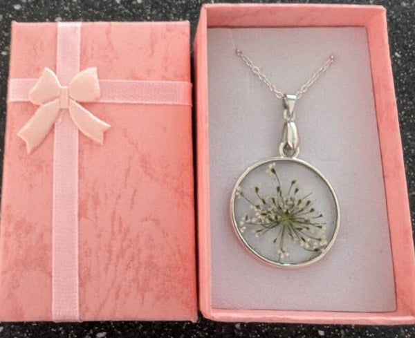 Round resin pendant finished with a white dried flower