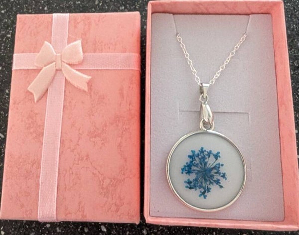 Round resin pendant finished with a blue dried flower
