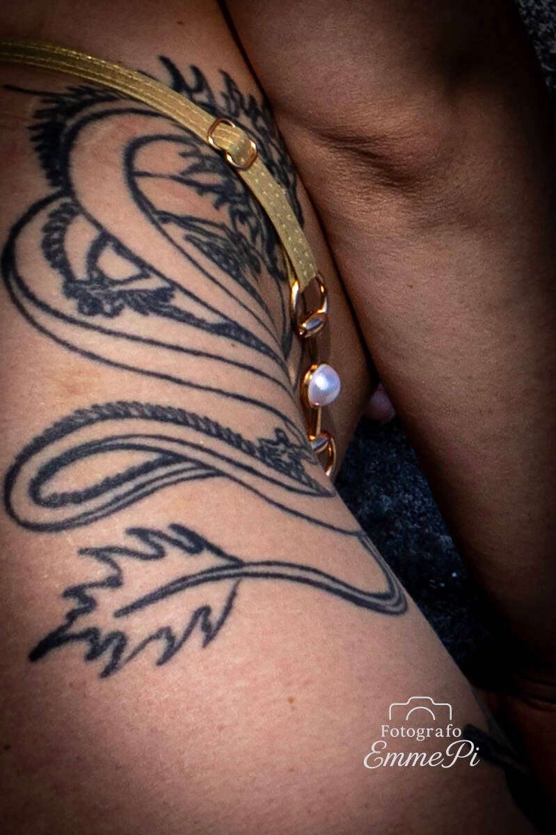 Primo piano di tatuaggio ornamentale sulla coscia femminile illuminato da luce morbida.