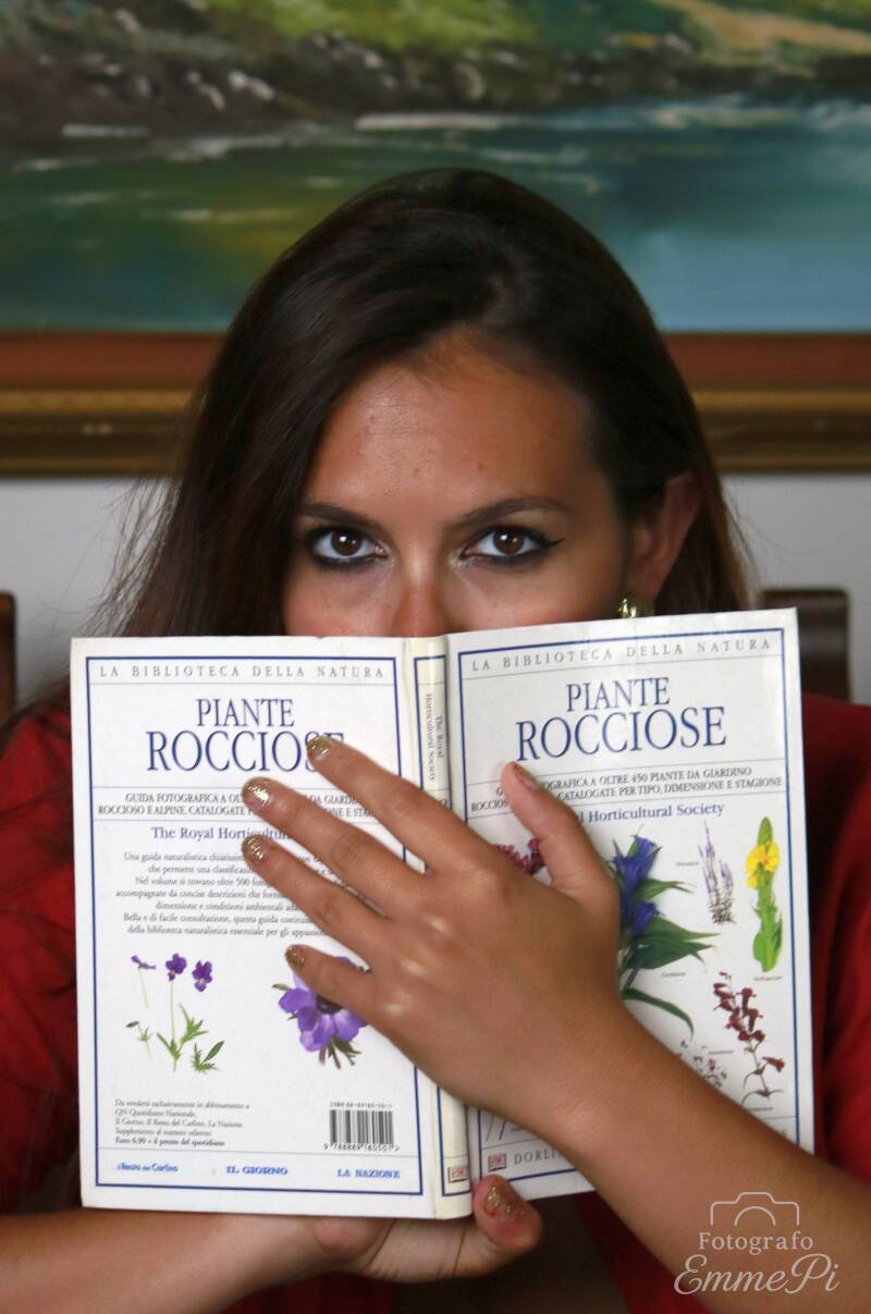 Dafne osserva l'obiettivo da dietro un libro aperto, lasciando scoperti soltanto gli occhi e parte del volto.