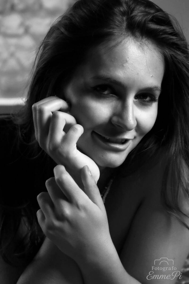 Ritratto in bianco e nero di Dafne sorridente, con le mani vicino al viso e lo sguardo rivolto verso l'obiettivo.