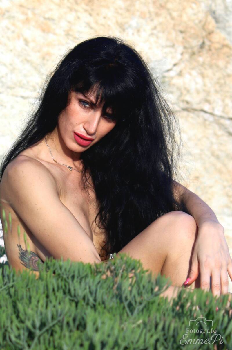 Melissa seduta tra la vegetazione alla Baia del Corvo con lo sguardo rivolto di lato