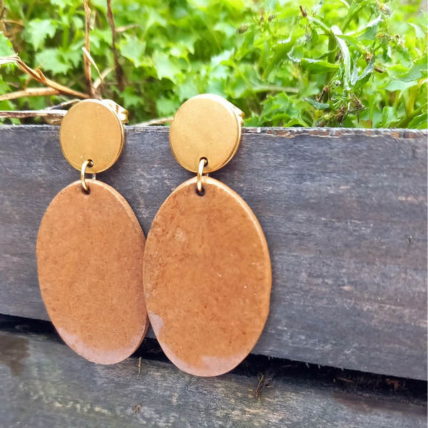 Licht bruine ovalen oorbellen aan gouden ronde oorstekers