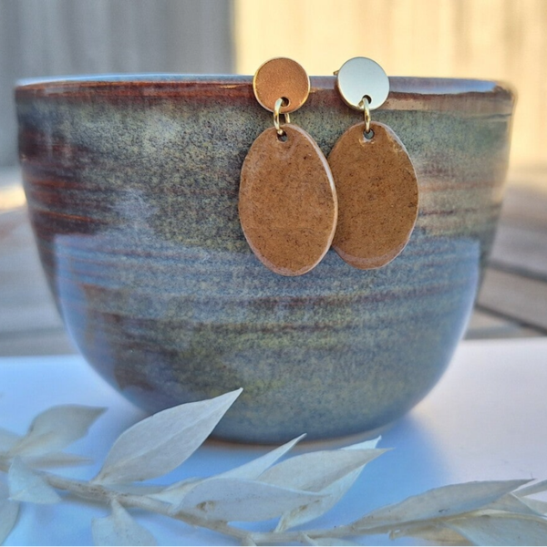 Licht bruine ovalen oorbellen aan gouden ronde oorstekers