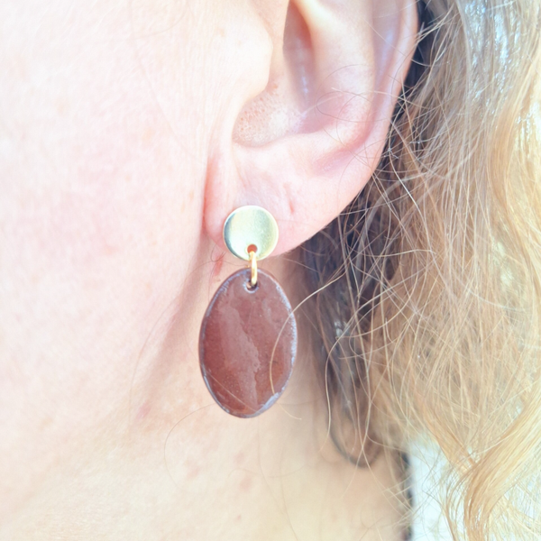 Donker bruine ovalen oorbellen aan gouden ronde oorstekers