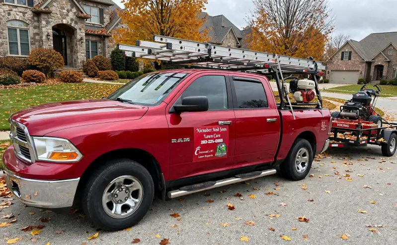 Fall gutter cleaning in Greater Cincinnati OH - Nienaber And Sons Lawn Care LLC red RAM truck with ladder rack and Exmark Viking mower on trailer ready for leaf removal and gutter cleaning in Mason, Sharonville, Bridgetown, Harrison OH - call 283-224-0555