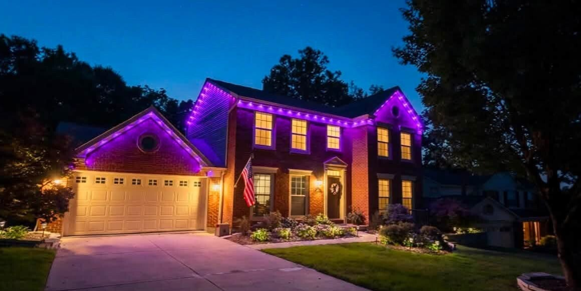 Residential brick home in Cincinnati, OH, illuminated by professional custom permanent purple LED holiday lights installed by Nienaber And Sons Lawn Care (283-224-0555), viewed at dusk with landscaping lights and a prominent company logo in the foreground