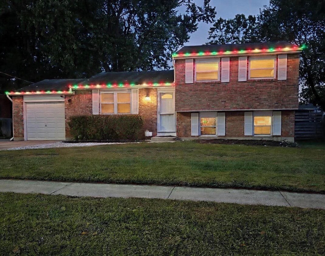 Professional Christmas light installation featuring classic red and green holiday lights along the rooflines of a brick split-level home in Cincinnati. 