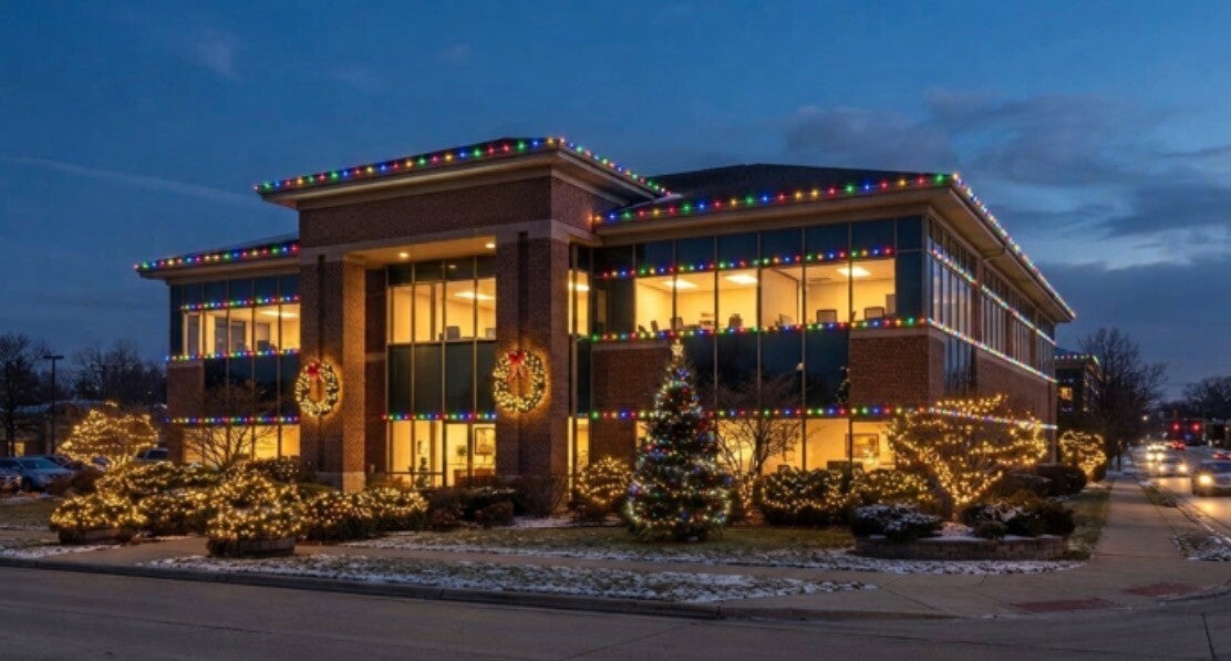Commercial Christmas light installation on an office building facade in Greater Cincinnati, including multi-colored trim, wreaths, and landscape lighting.
