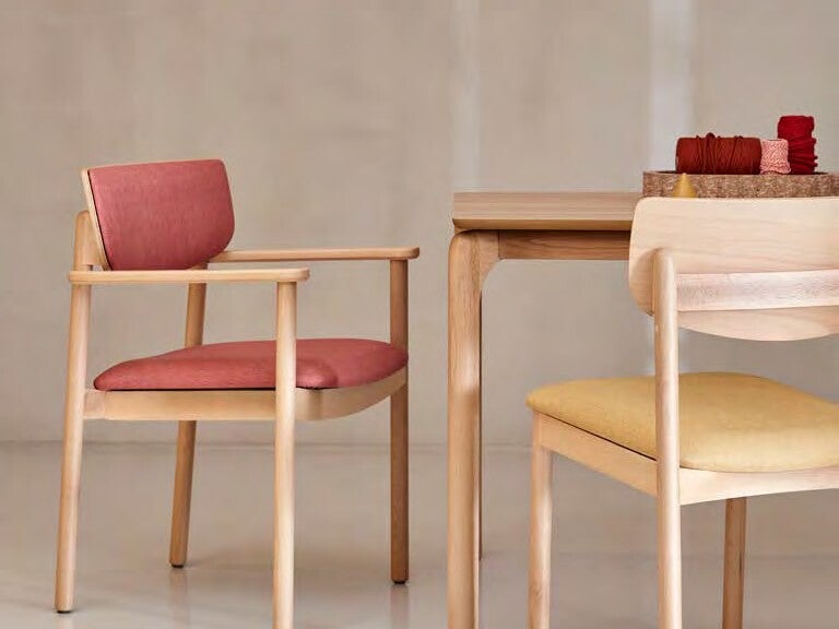 Chaises colorées à accoudoirs autour d'une table de résidence seniors