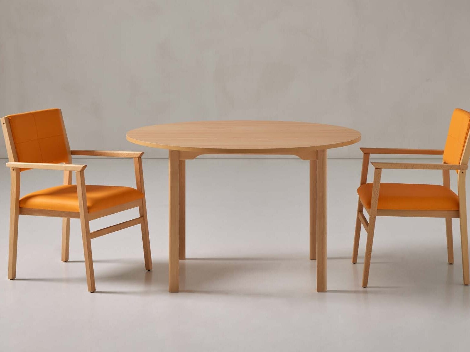 Fauteuils de table orange et table ronde en bois pour EHPAD