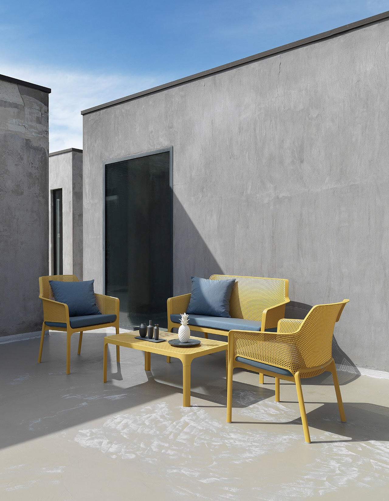 Ensemble Nardi Net jaune : banc, fauteuils Net Relax et table basse sur une terrasse