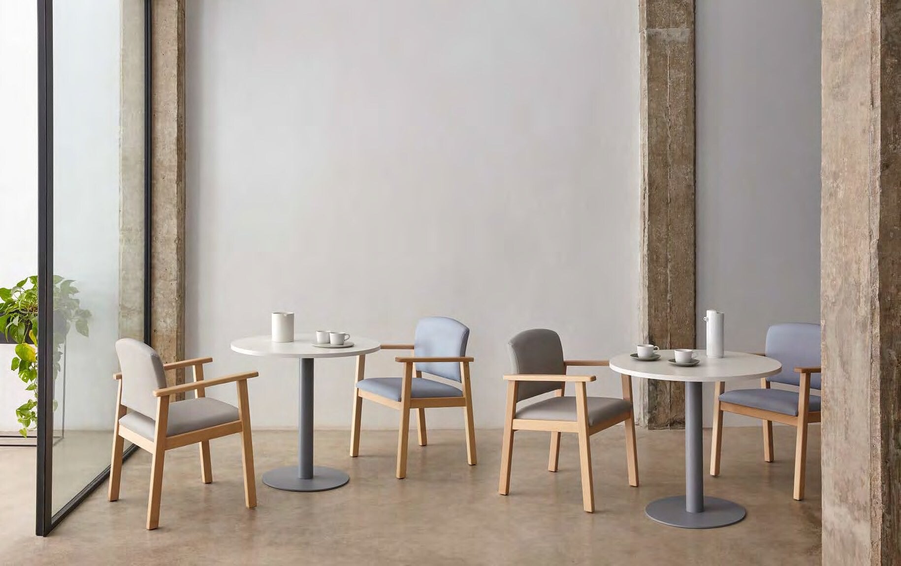 Tables rondes à piètement central et chaises à accoudoirs pour salle de restaurant