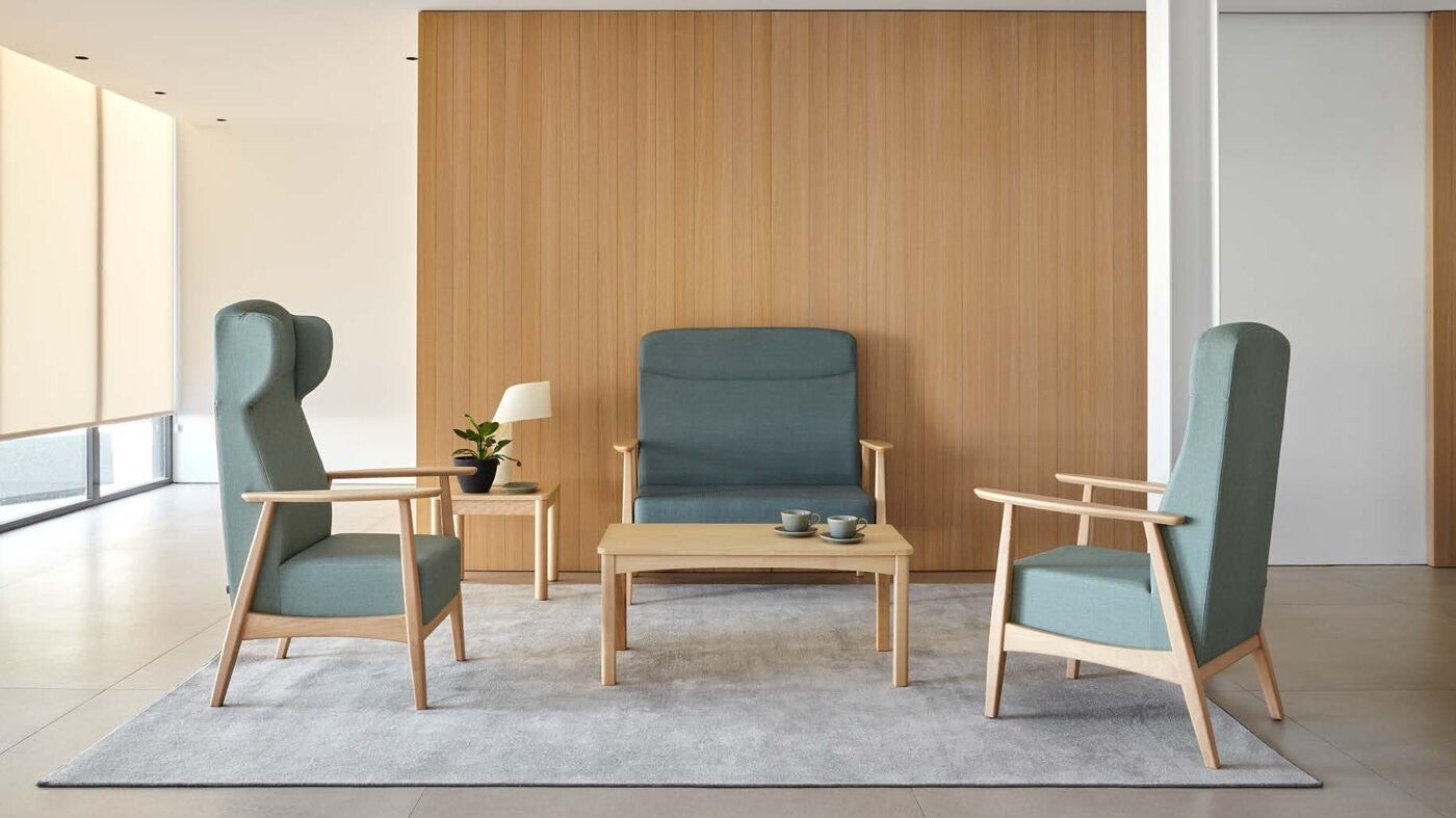 Salon d'EHPAD avec fauteuils à dossier haut, canapé et table basse en bois