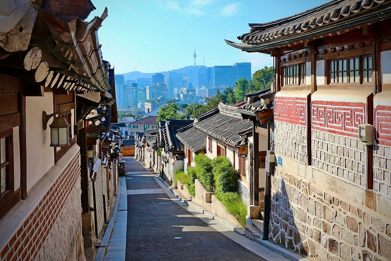 Een rustige woonstraat in Bukchon met traditionele hanok en Seoul in de achtergrond