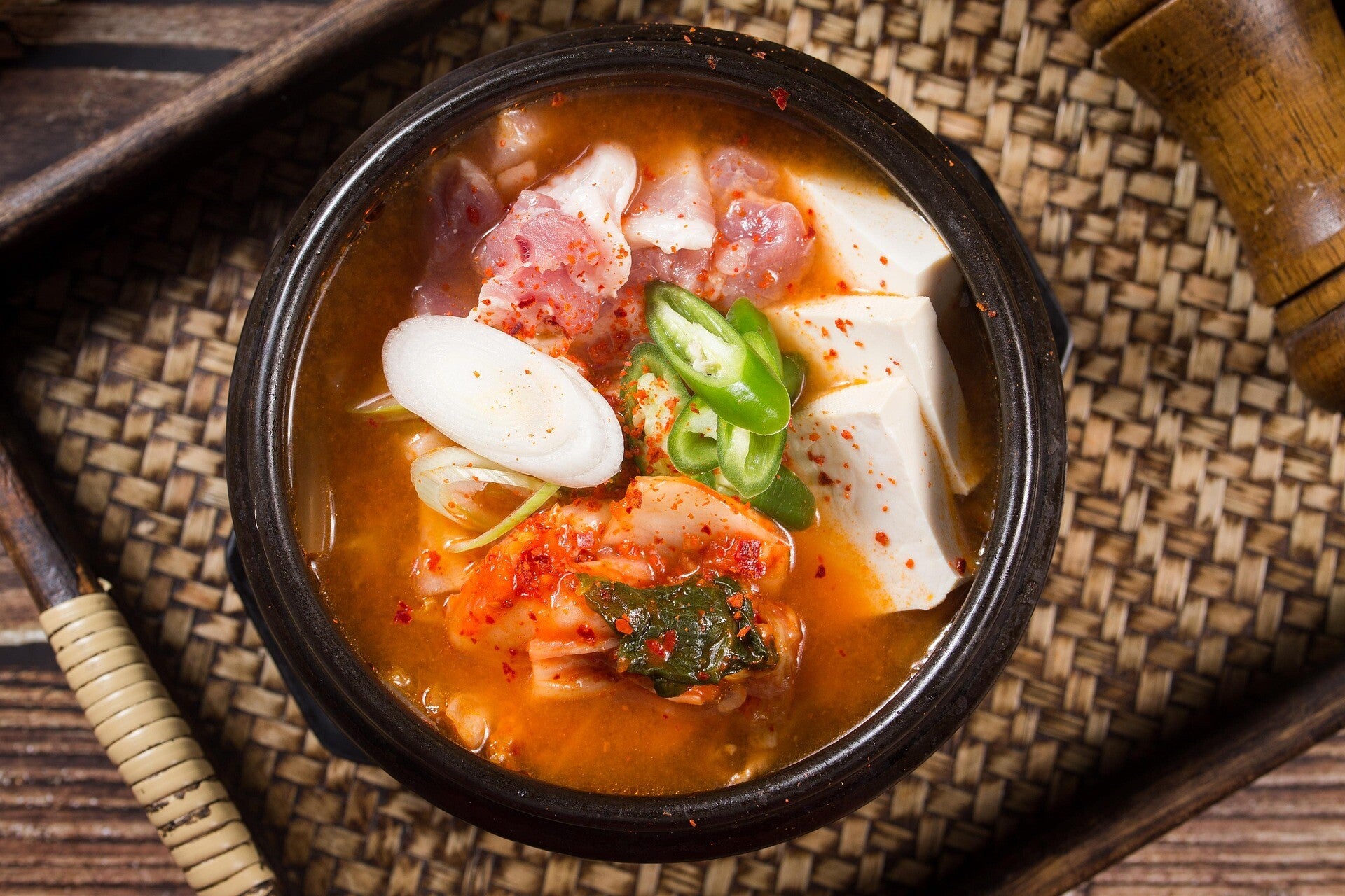 Een dampende pot kimchi-jjigae laat zien hoe een paar vertrouwde ingrediënten kunnen uitgroeien tot een van de meest karakteristieke gerechten van de Koreaanse thuiskeuken.