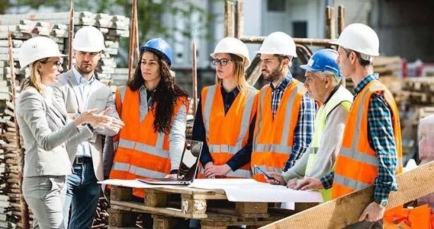 Groupe de travailleurs équipés d'EPI participant à un briefing de sécurité sur un chantier de construction.