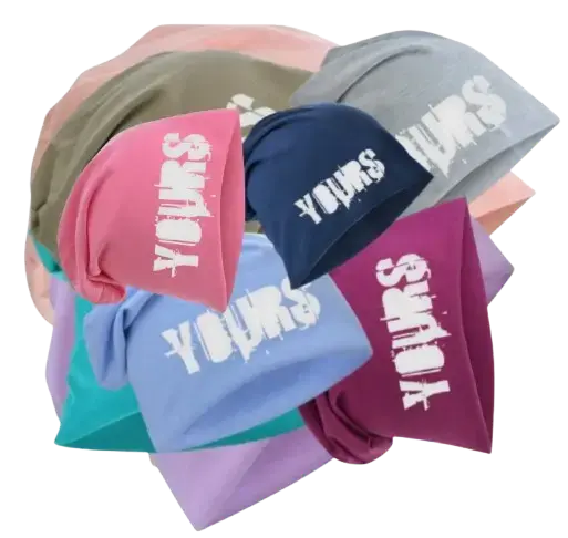 Ein Stapel farbenfroher Slouch-Beanies der Marke YOURS mind in Farben wie Rosa, Blau, Grau und Beere, jeweils bedruckt mit einem weißen, vertikalen „YOURS“-Schriftzug. Link führt zur Produktseite.
