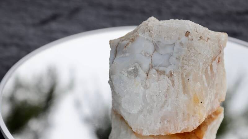 Raw Golden Healer Quartz and smooth white chalcedony matrix specimen held outdoors in natural light.