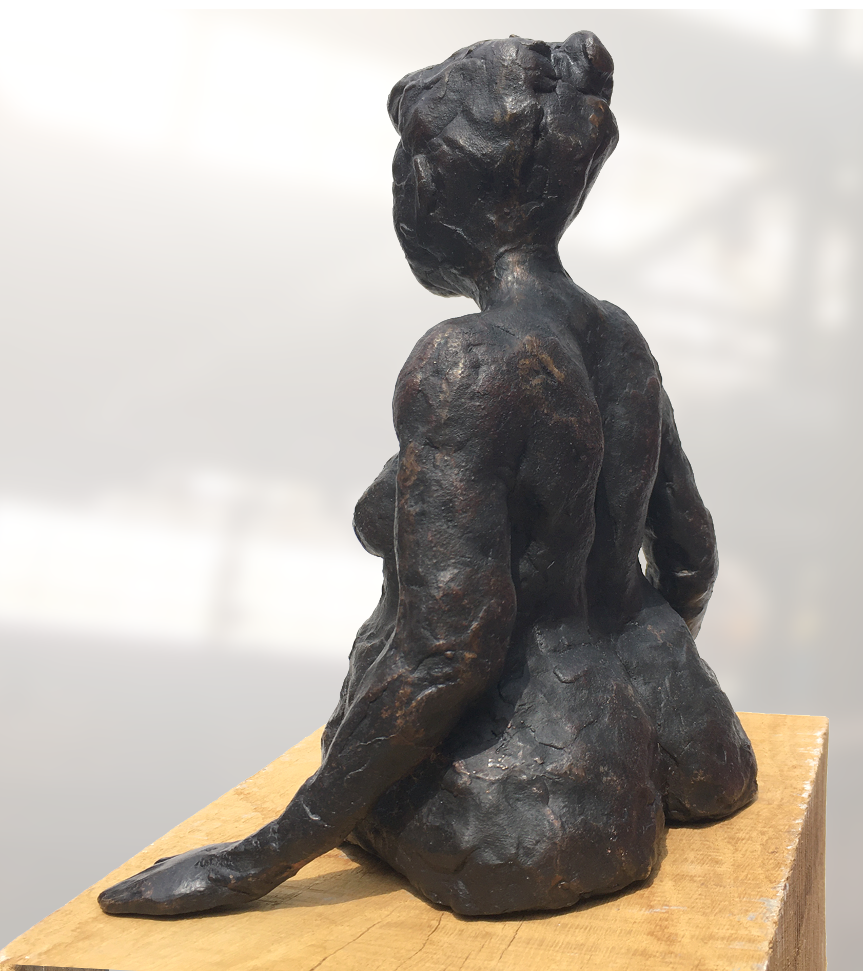 De achterkant van een bronzen beeld van een baadster  op een houten sokkel