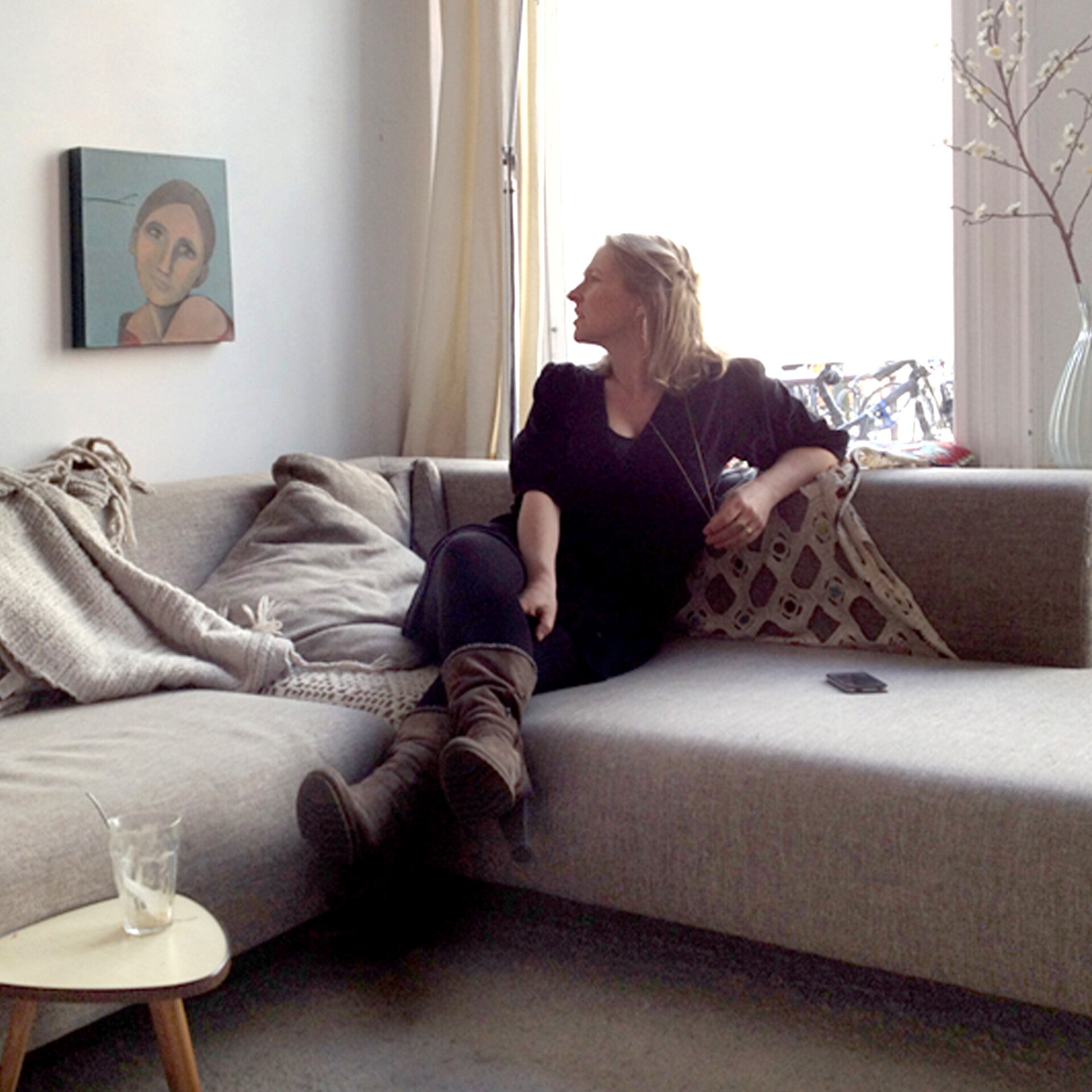 Vrouw zit op een bank en kijkt blij naar een schilderij aan de muur