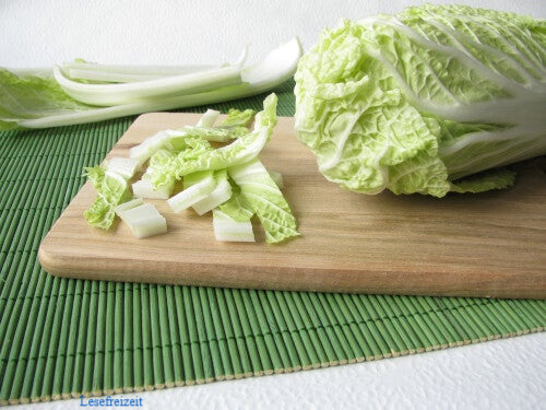 Chinakohl liegt auf einem Schneidebrett und wird kleingeschnitten.