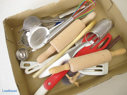 Verschiedene ausgemistete Küchenutensilien wie Siebe, Pflannenwender, Tortenheber und Schneebesen in einem Karton.