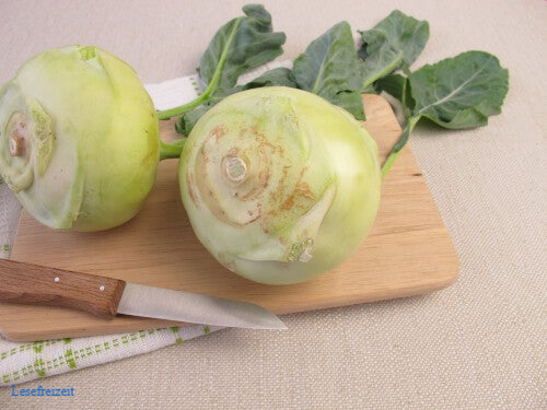 Kohlrabi und ein Küchenmesser auf einem Schneidebrett.