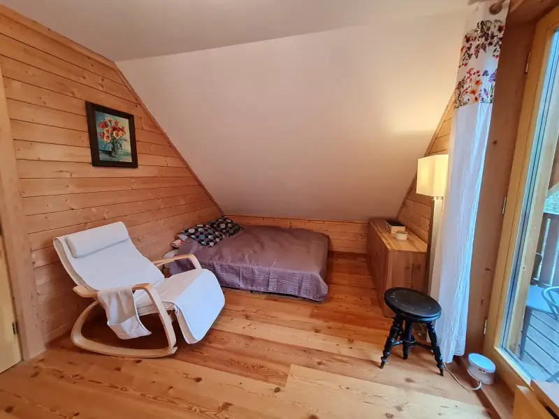  Gemütliches Dachgeschoss-Schlafzimmer im Blockhaus Hengsttal mit Schaukelstuhl, Holzwänden und Balkonzugang mit Blick ins Hengsttal