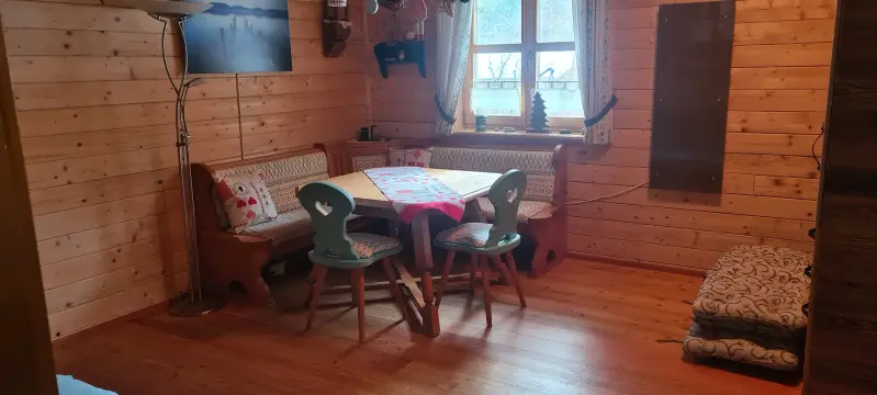 Gemütliche Essecke im Blockhaus Hengsttal mit rustikaler Holz-Eckbank, bestickten Kissen und liebevoller Dekoration.