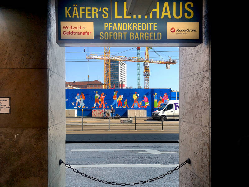 Durchblick – Zwischen Baukränen und Bargeld. Wo die Stadt in den Himmel wächst, wachsen oft auch die Kosten. Ein gerahmter Blick auf das München der Gegenwart.