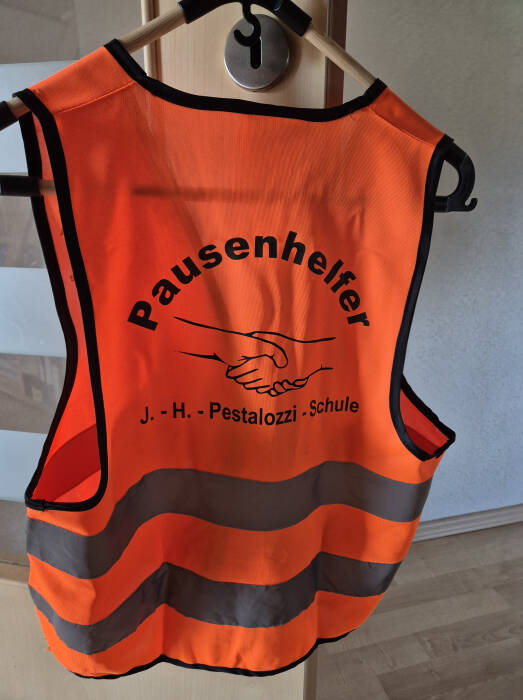 eine der gesponserten Pausenhelferwesten in orange mit Aufschrift Pausenhelfer