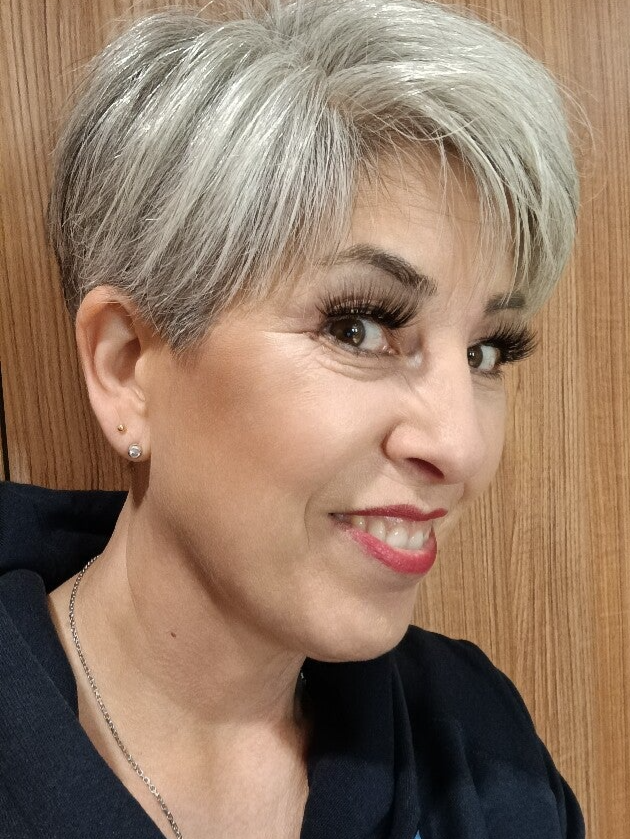 Grauhaarige Frau vor einer Holzwand