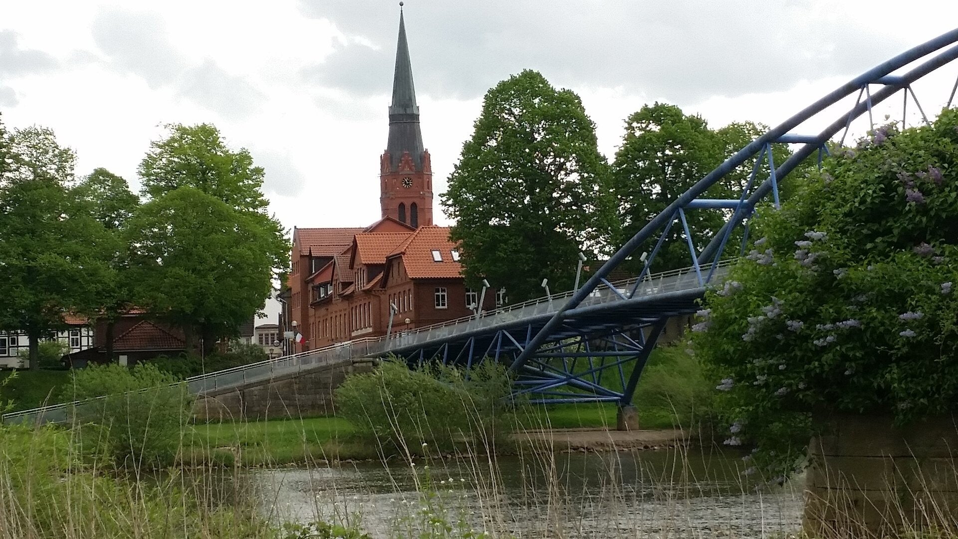 Von der anderen Nienburger Weserseite schaut man auf die Fußgängerbrücke und den markanten Kirchturm von Sankt Martin.