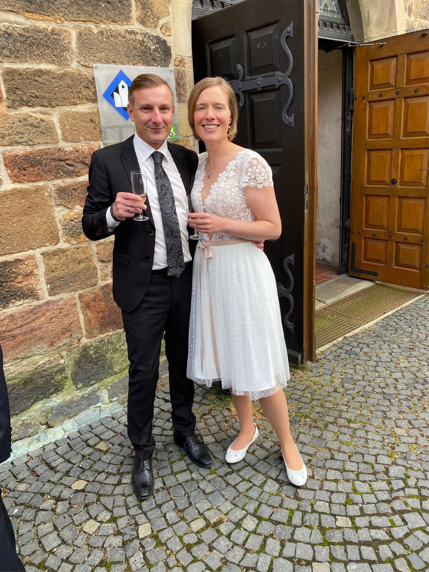 Stefanie Duensing steht im Hochzeitskleid mit ihrem Ehemann vor der Nienburger Kirche Sankt Martin.