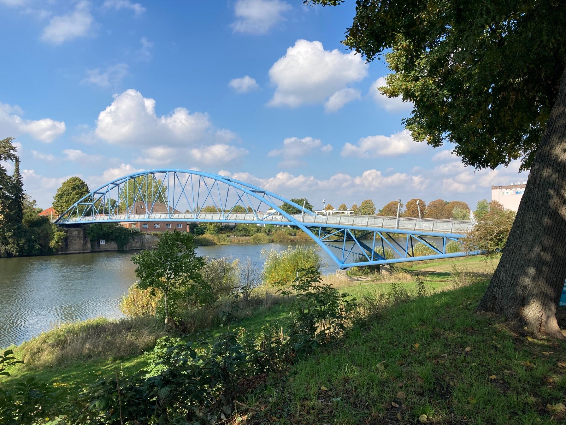 Die blaue Fußgängerbrücke in Nienburg führt über die Weser. Sie liegt bei blauem Himmel in der Sonne.