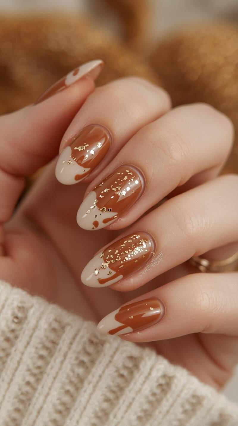 _a-close-up-of-a-female-hand-with-medium-oval-nails-the-base-is-a-creamy-brown-with-glossy-caramel-colored-drip-designs-on-each-nail-accented-with-tiny-gold-flakes-3-standard.jpg