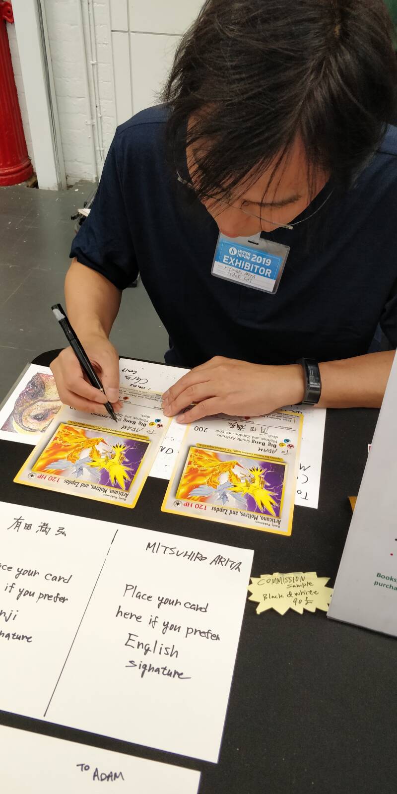 Mitsuhiro Arita Signing Pokemon cards during Hyper Japan 2019