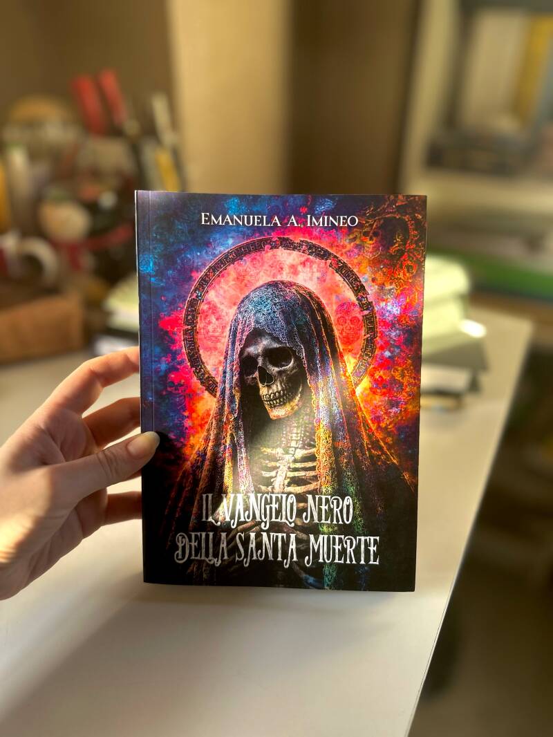 Foto in cui tengo in mano il libro Il Vangelo nero della Santa Muerte di Emanuela A. Imineo