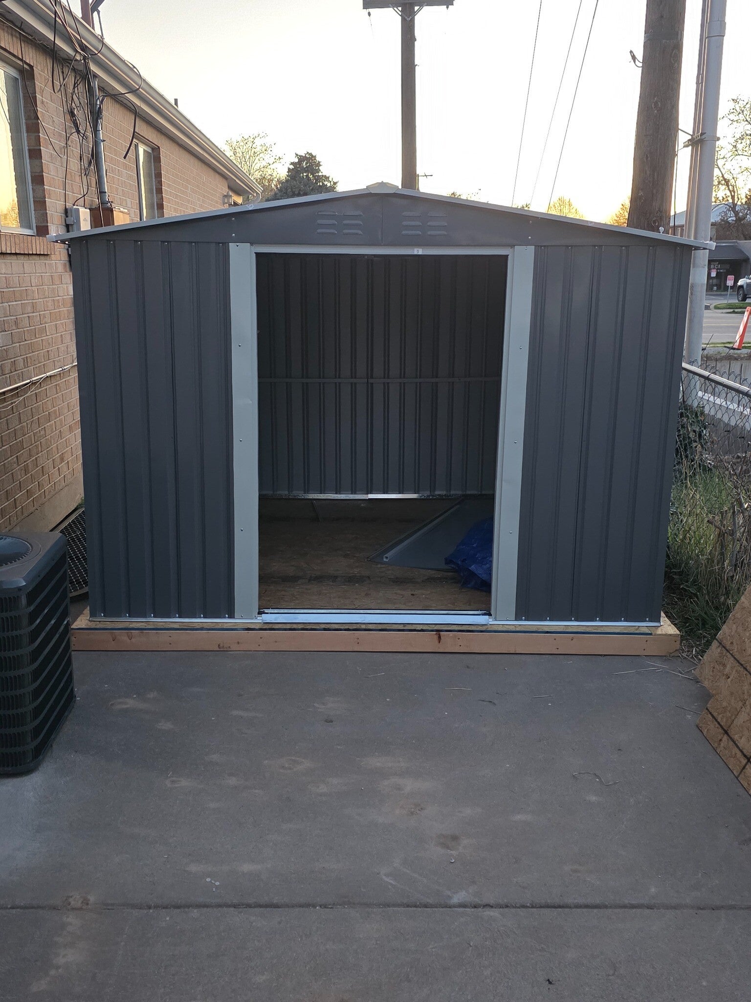 Gray metal storage shed on a wood base during assembly in Kaysville