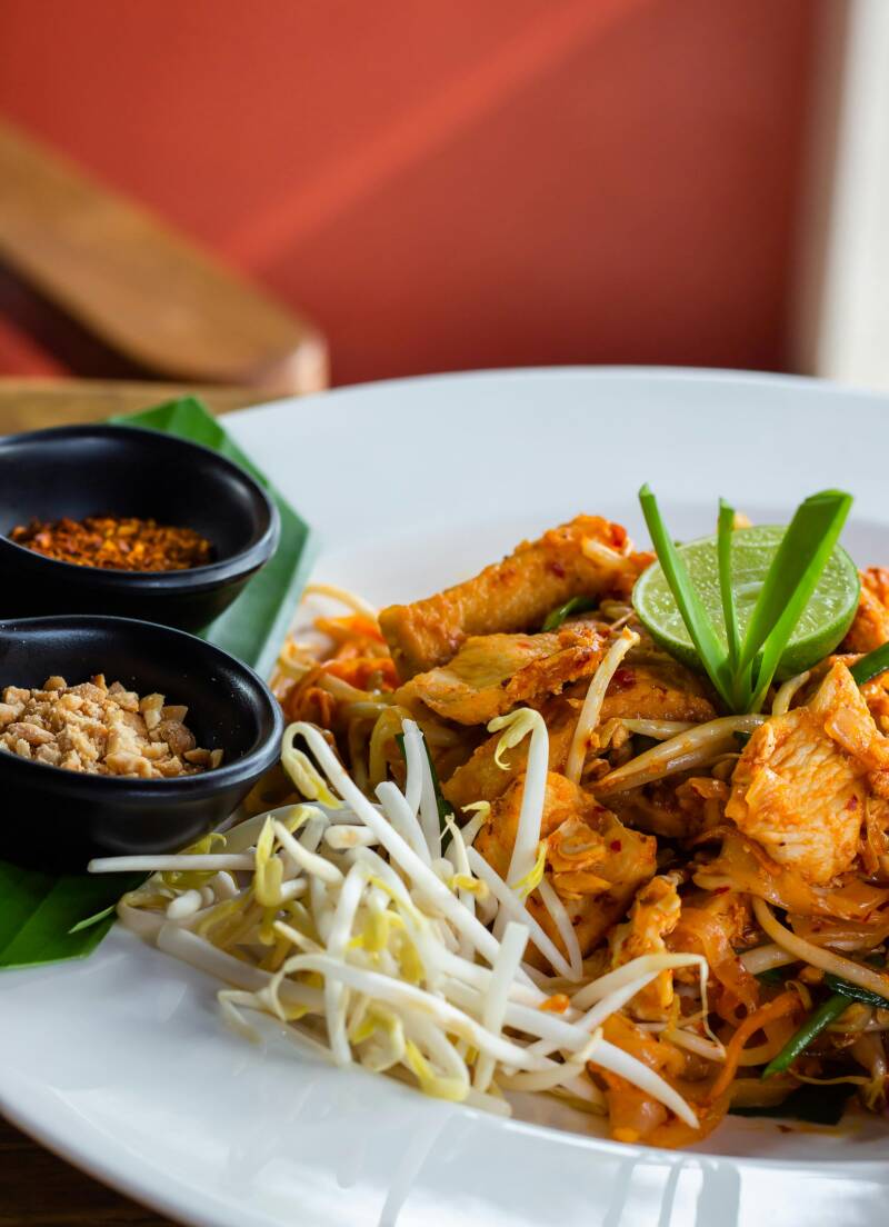 Ein frisch zubereitetes thailändisches Pad Thai mit Erdnüssen, Sprossen, Limette und Hähnchen.