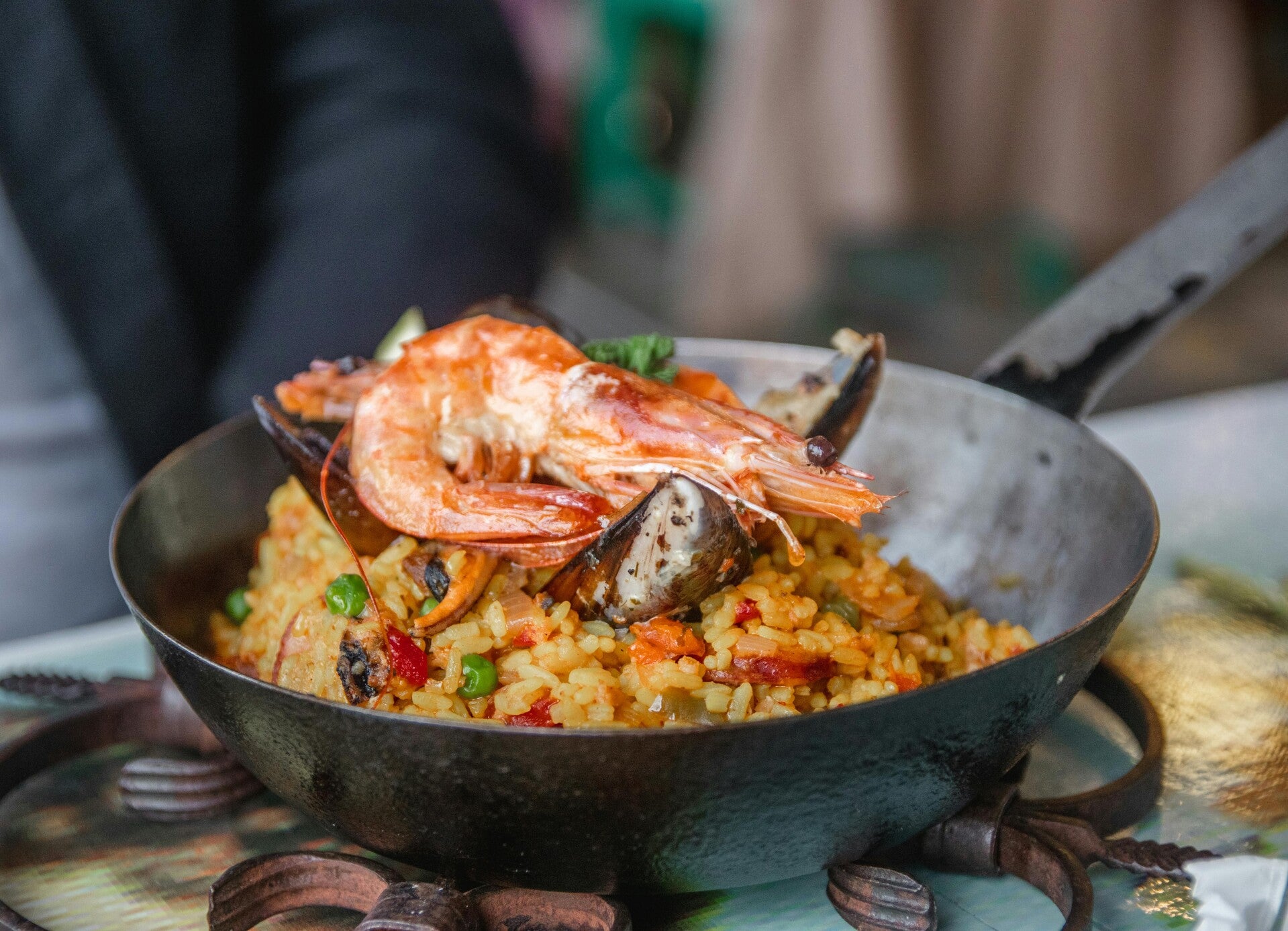 Eine Pfanne mit frisch zubereiteter spanischer Paella, garniert mit großen Garnelen und Muscheln.