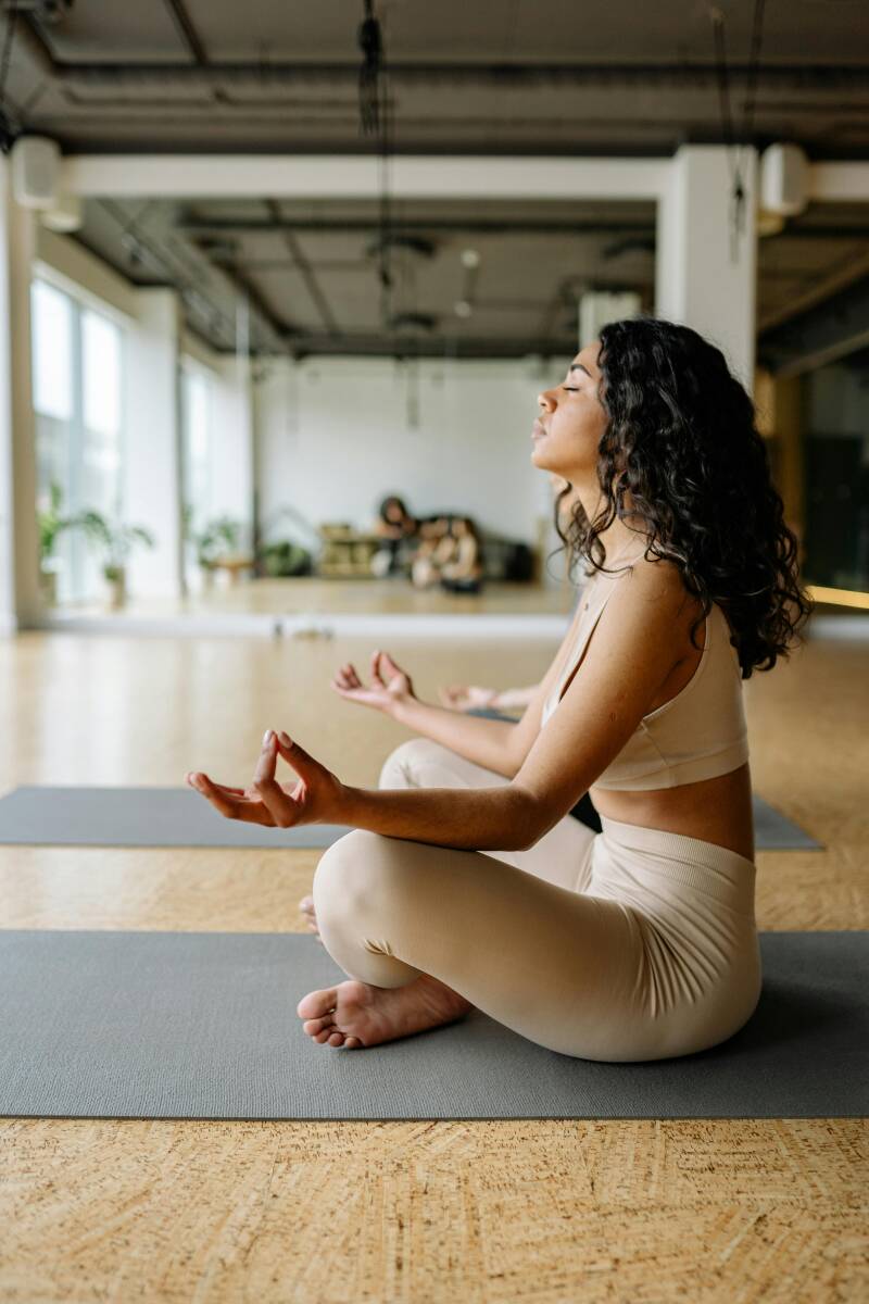 Nahaufnahme einer Frau in Meditationshaltung bei einer Yoga-Session.