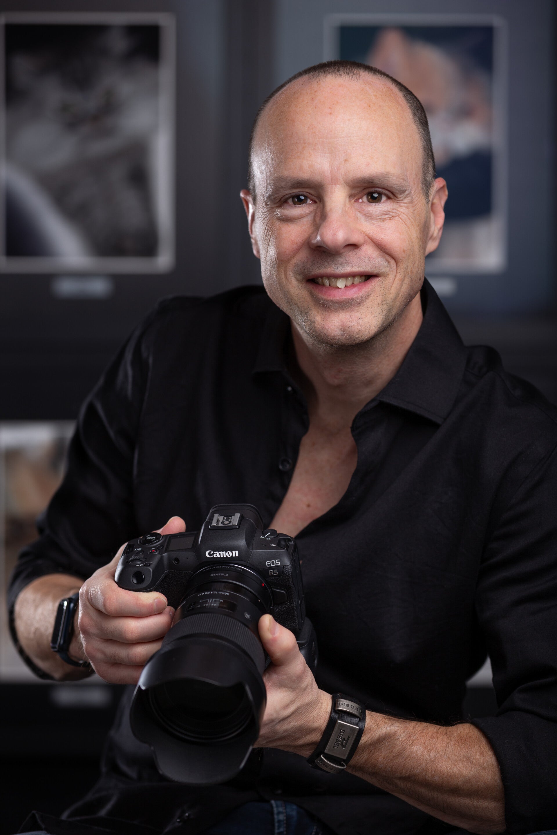 Photo de Martin Soucy, graphiste et photographe. Homme aux cheveux très courts vêtu de noir avec un appareil photo Canon en main.