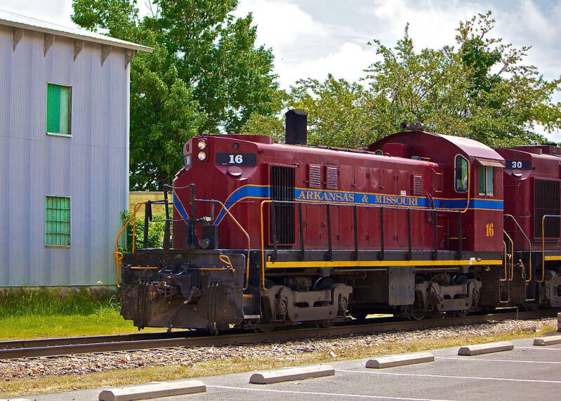 The Arkansas & Missouri Railroad's Alco T-6 #16 leads the daily local past Frisco Park in Rogers, AR.