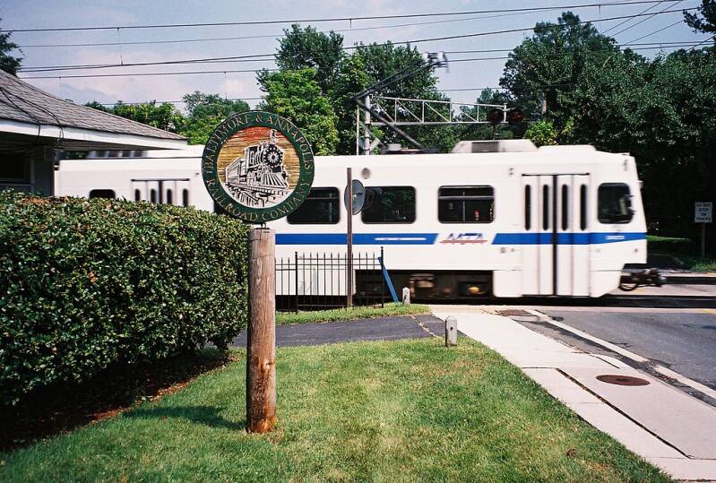 A southbound MTA Light Rail train passes the old B&A Linthicum Heights station at Maple Road,  with a B&A Railroad commemorative marker in the foreground.