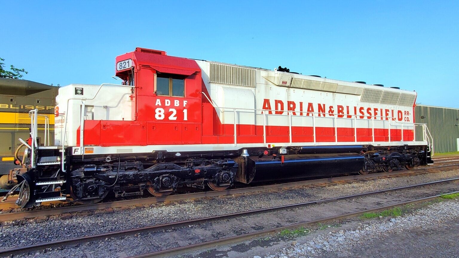 a red and white diesel-electric locomotive in an in dustrial setting
