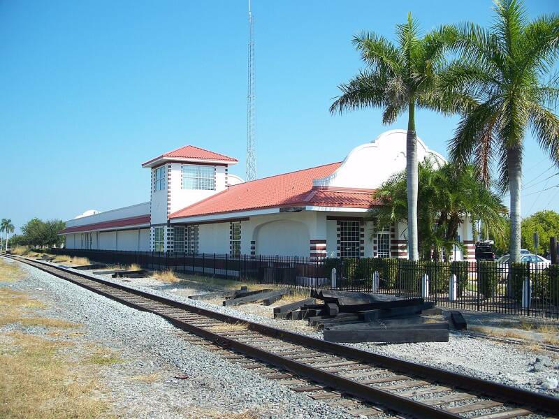 a Spanish-style depot next to a railroad track