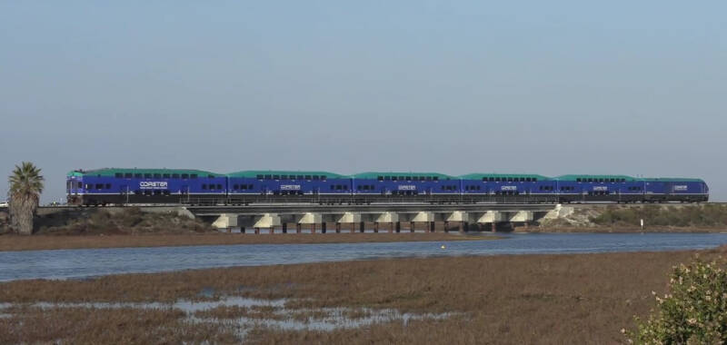 A Coaster train passes over a new concrete bridge (as part of a bridge replacement project) near the Torrey Pines State Natural Reserve.